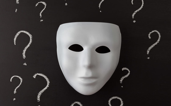 Máscara blanca sobre fondo negro con signos de interrogación